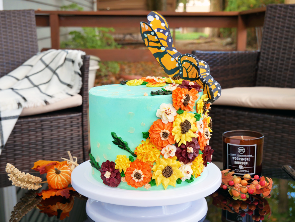 Cinnamon Apple Cake with Apple Pie Filling, Maple Simple Syrup, and Vanilla Bean Buttercream. Decorated with buttercream fall flowers and fondant monarch butterflies taking flight.