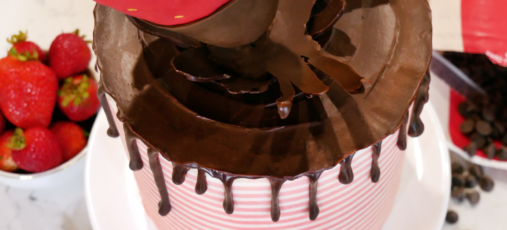 Gravity-defying chocolate-covered strawberries cake with a striped buttercream fondant.