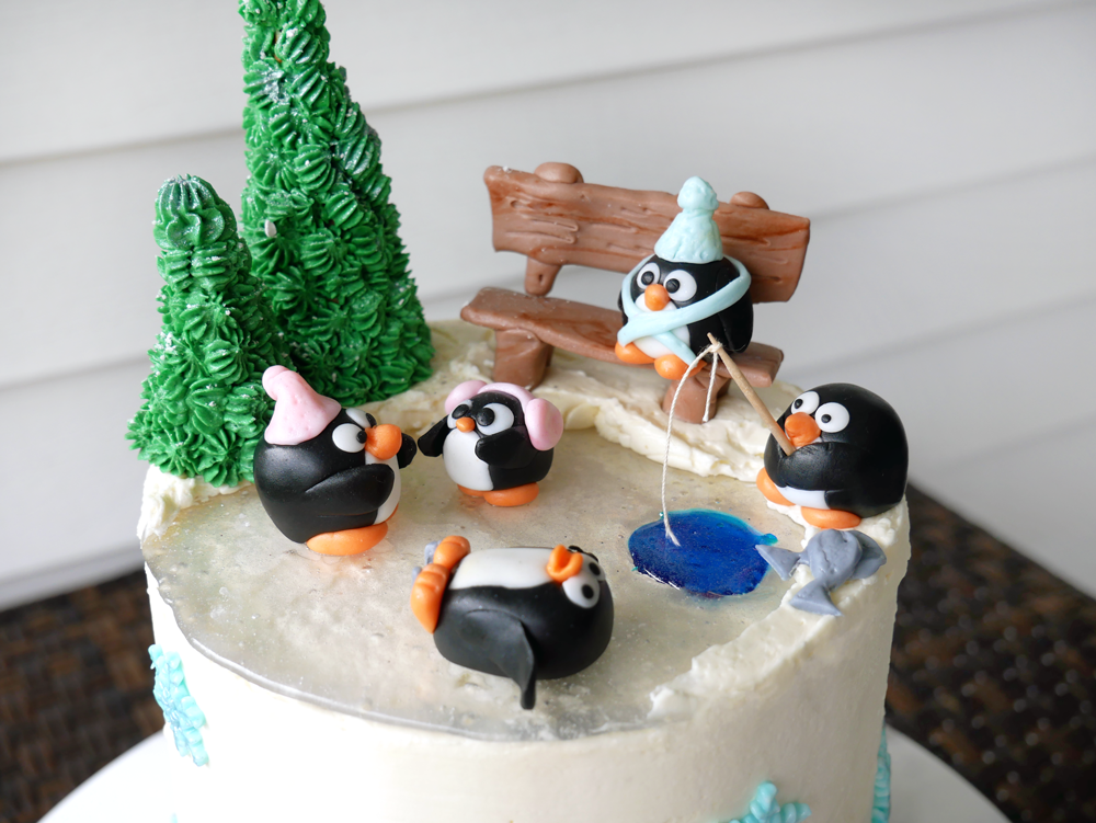 Delicious peppermint hot chocolate cake with chocolate ganache, marshmallowy swiss meringue buttercream, and crunchy peppermint candy filling. Decorated with an adorable fondant and isomalt penguin ice skating rink!