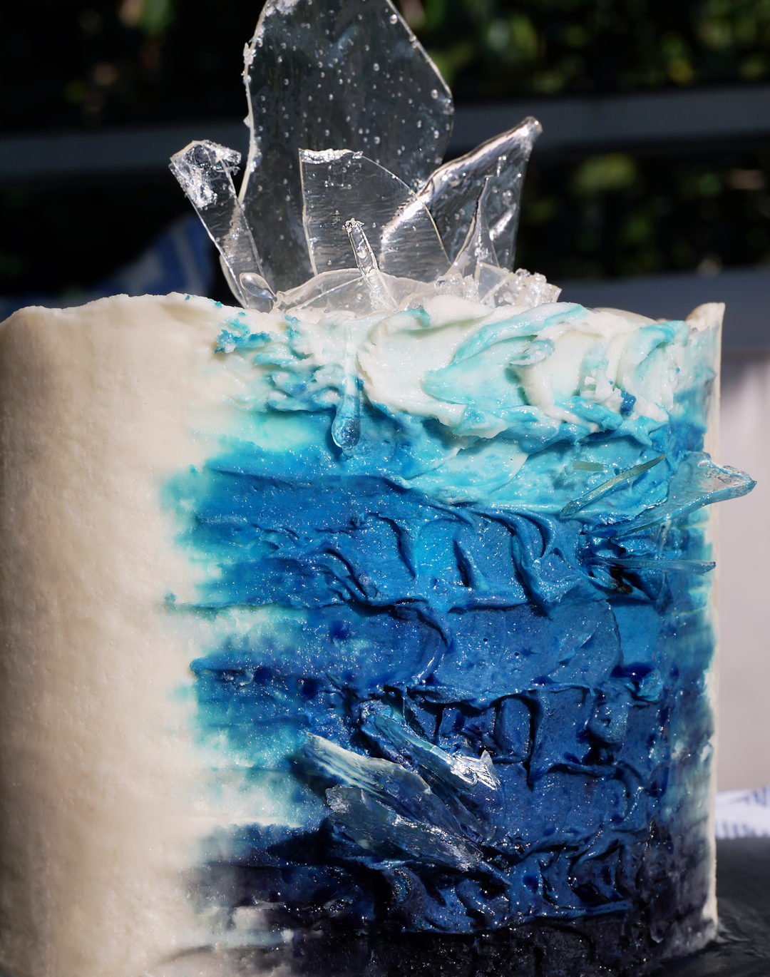 buttercream painted glacier inspired cake with palette knife painting tehcniques and isomalt sugar sail