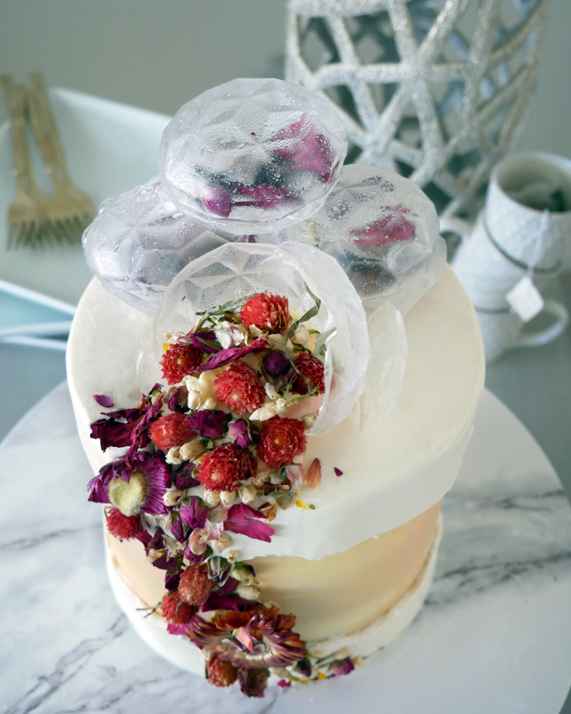 Youthberry Tea white cake with raspberry filling and orange faux swiss meringue buttercream, topped with isomalt teabag bombs and edible flowers.