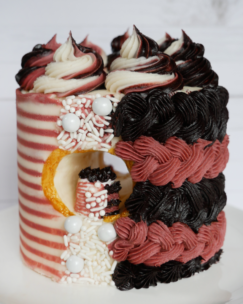 A mini striped cake with a horizontal hole through the middle and an even smaller cake inside of it. 