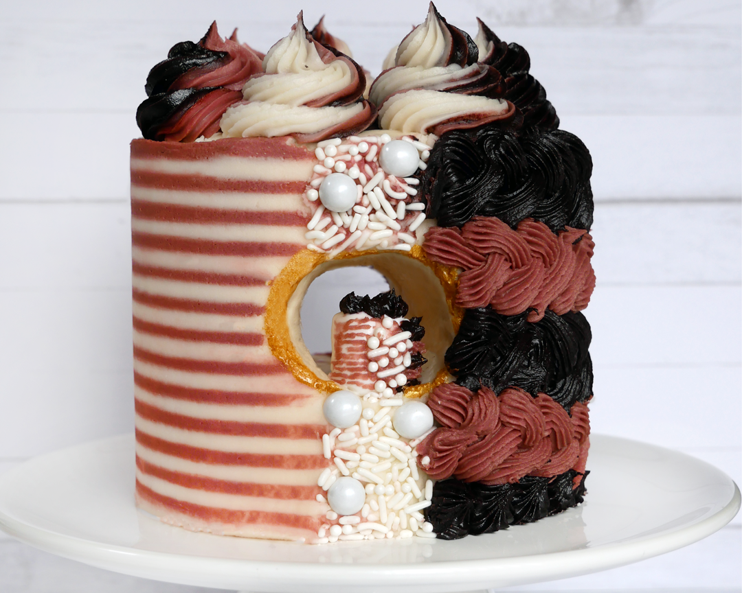 A mini striped cake with a horizontal hole through the middle and an even smaller cake inside of it.